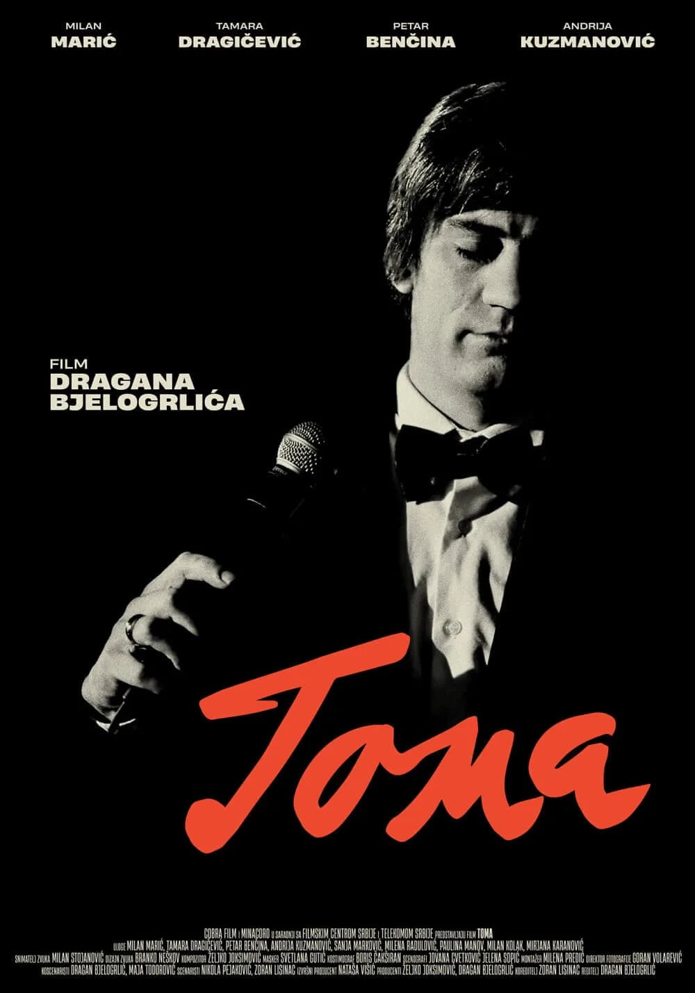 Plakat filma „Toma“: muškarac u smokingu s leptir-mašnom i mikrofonom u ruci, crno-bela fotografija, crveni naslov